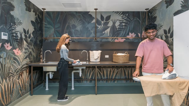 Students ironing and washing with tropical mural Laundry room at UniLodge Melbourne Flagstaff in Melbourne Student Accommodation