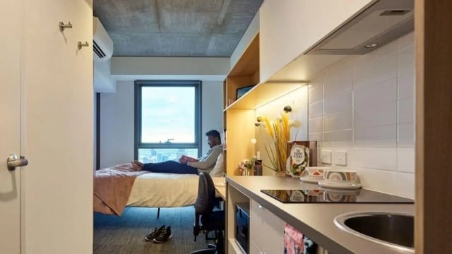 Bed desk kitchen counter sink and person bedroom kitchen at Unilodge Melbourne City in Melbourne Student Accommodation