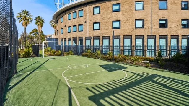 Small soccer court with building and palm trees exterior at UniLodge Park Avenue in Melbourne Student Accommodation