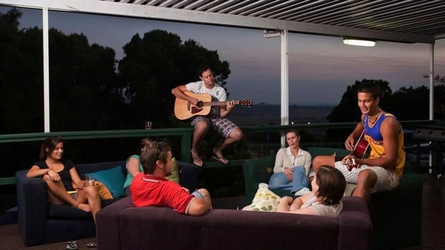 People relaxing on sofas while playing guitar outside living room at Unilodge SCU Lismore Orion in Lismore Student Accommodation