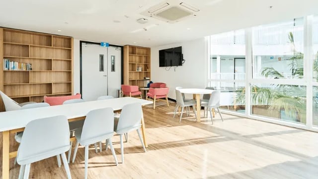 Table chairs chairs bookshelves TV living room at Unilodge SCU Lismore Orion in Lismore Student Accommodation