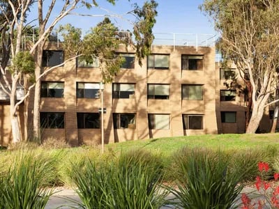 Building with many windows and grassy lawn exterior at @the Lodge UNIVERSITY LIVING in Weatherford Student Accommodation