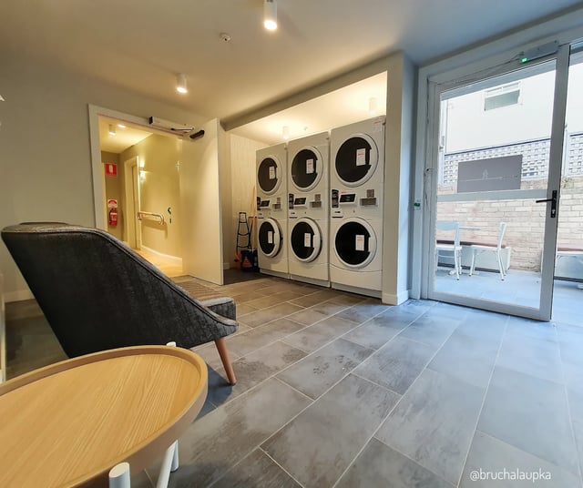 Laundry room with washing machines and seating area at UKO Paddington in Sydney Student Accommodation