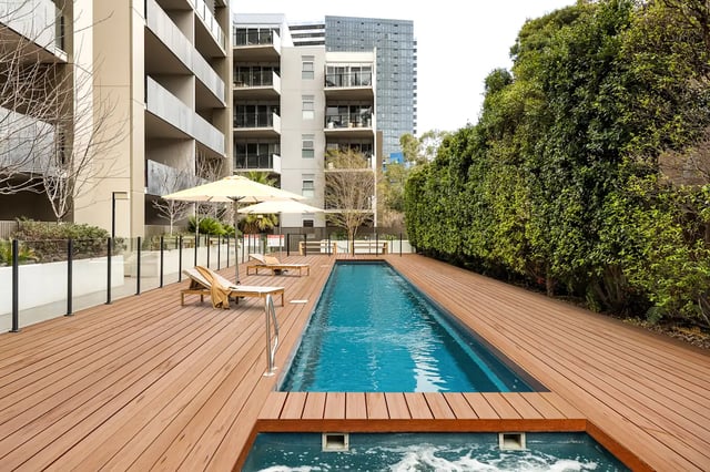 Pool with lounge chairs and umbrellas exterior at UKO Royal Park in Melbourne Student Accommodation