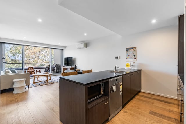Sofa coffee table TV kitchen island living area kitchen at UKO Royal Park in Melbourne Student Accommodation