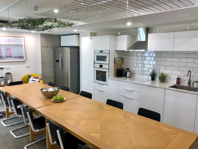 Large wooden table chairs stainless steel fridge kitchen area at UKO Stanmore in Sydney Student Accommodation