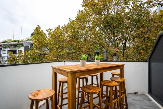 Wooden table with stools and plants balcony living area at UKO Surry Hills in Sydney Student Accommodation