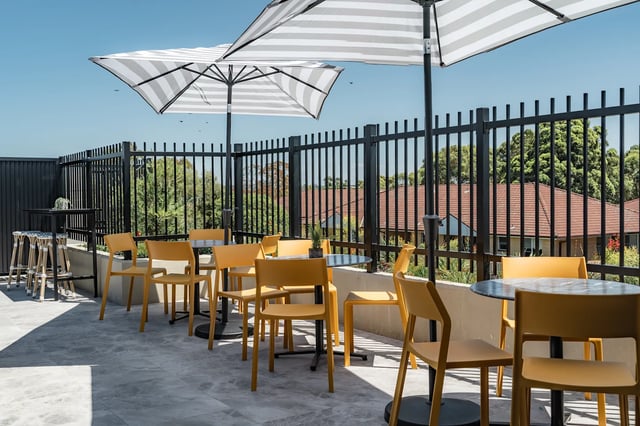 Outdoor seating area with yellow chairs and umbrellas patio area at UKO Sutherland in Sydney Student Accommodation