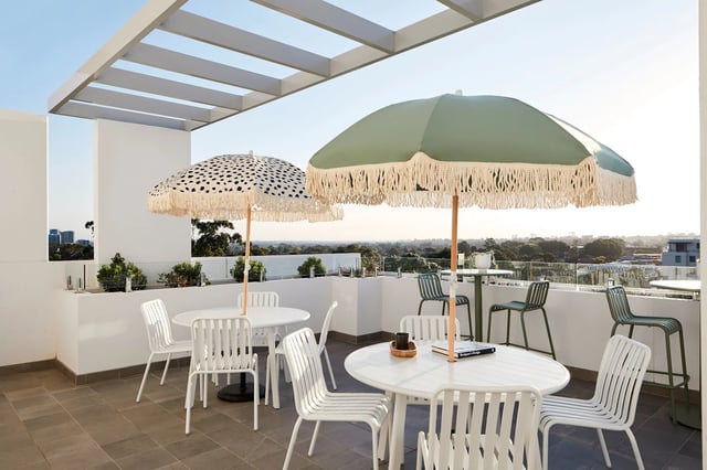 Outdoor seating area with tables umbrellas and chairs exterior at UKO West Ryde in Sydney Student Accommodation