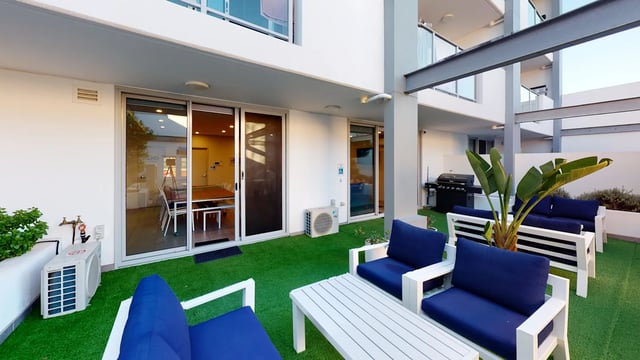 Blue sofas white tables air conditioning barbecue patio area at UKO West Ryde in Sydney Student Accommodation