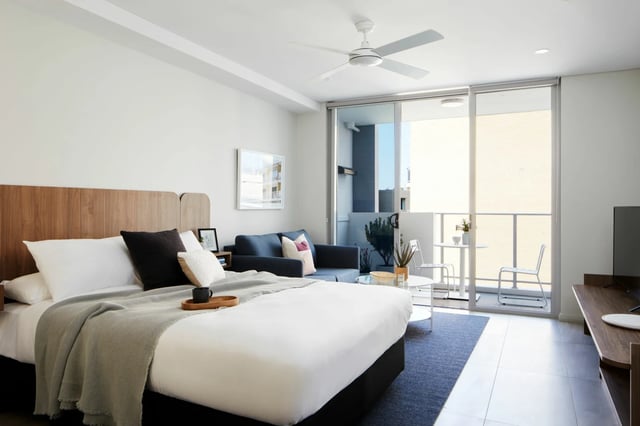 Bed sofa and balcony with chairs living room at UKO West Ryde in Sydney Student Accommodation