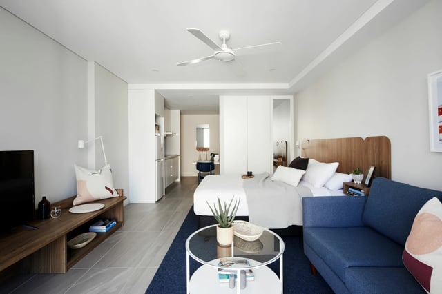 Bed couch kitchen and ceiling fan living room at UKO West Ryde in Sydney Student Accommodation