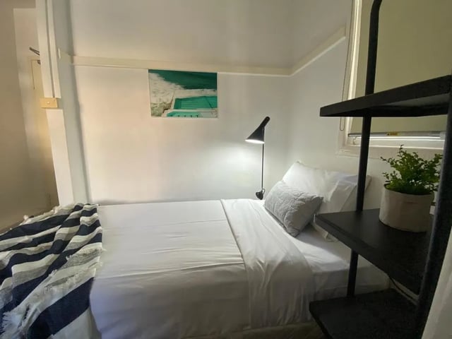 Bed with striped blanket lamp plant Bedroom at ume 148 Darlinghurst Village in Sydney Student Accommodation