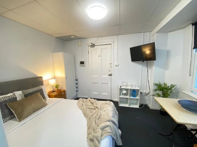 Bed table television plant and door bedroom at ume 148 Darlinghurst Village in Sydney Student Accommodation