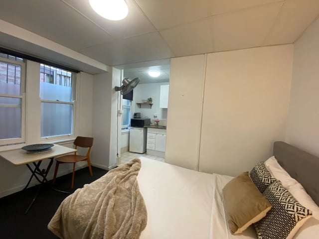 Bed desk fan small kitchen studio apartment at ume 148 Darlinghurst Village in Sydney Student Accommodation