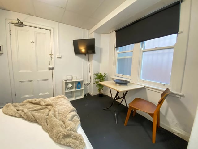 Bed TV shelf table chair window living room at ume 148 Darlinghurst Village in Sydney Student Accommodation
