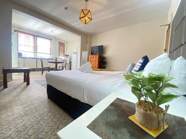 Bed pillows dresser and kitchenette studio apartment at ume 150 Darlinghurst Village in Sydney Student Accommodation