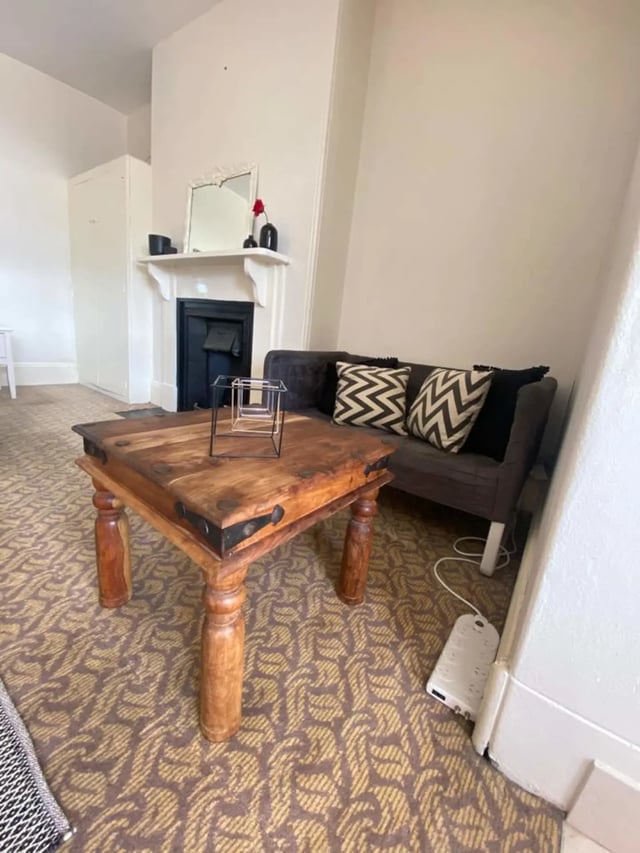 Wooden table sofa with patterned pillows fireplace living room at ume 150 Darlinghurst Village in Sydney Student Accommodation
