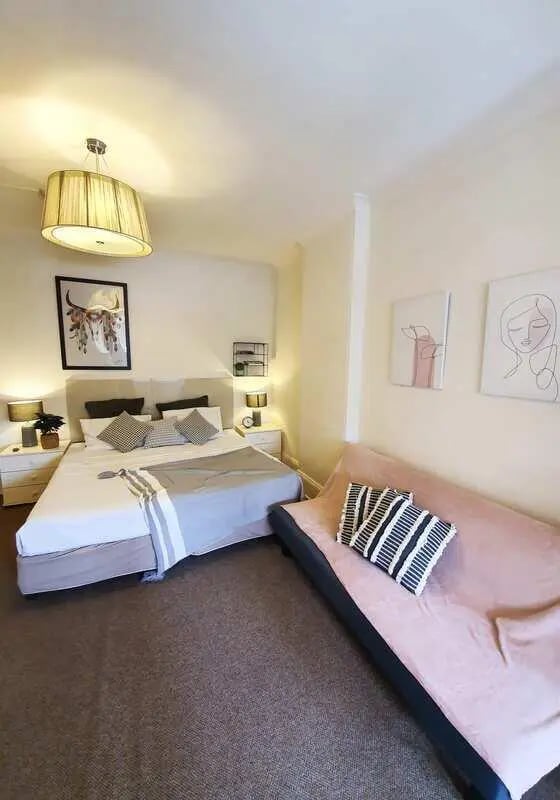 Bed and sofa with decorative pillows bedroom at ume 152 Darlinghurst Village in Sydney Student Accommodation