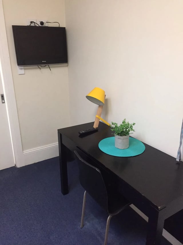 Desk television remote plant and yellow lamp study area at ume Redfern in Sydney Student Accommodation