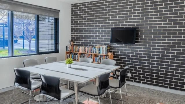 Table chairs bookshelf TV black brick wall common area at Western Sydney University Hawkesbury Village in Sydney Student Accommodation