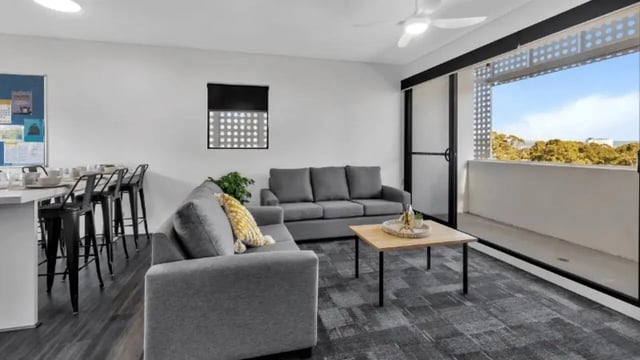 Gray sofas coffee table bar stools living room at Western Sydney University Penrith Village in Sydney Student Accommodation