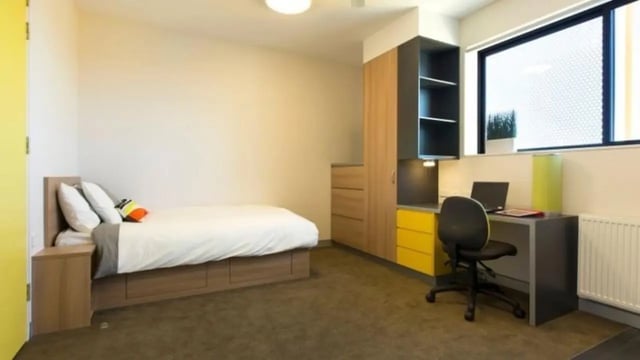 Bed pillows desk chair laptop shelves bedroom at Western Sydney University Penrith Village in Sydney Student Accommodation