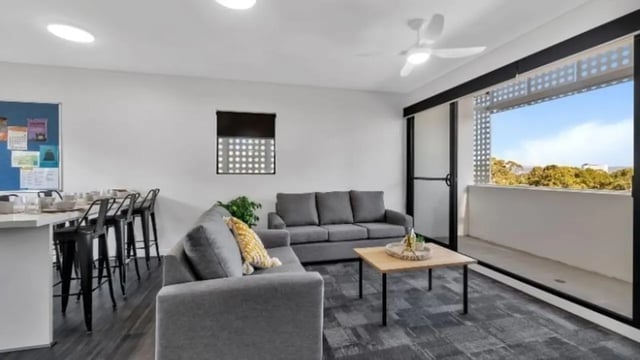 Sofas coffee table bar stools and balcony Living room at Western Sydney University Penrith Village in Sydney Student Accommodation