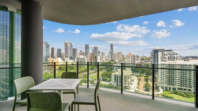 Table chairs with city view balcony exterior at Realm Kangaroo Point in Brisbane Student Accommodation