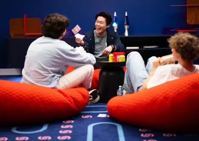 Three students playing cards on beanbags living room at Scape Leicester in Melbourne Student Accommodation