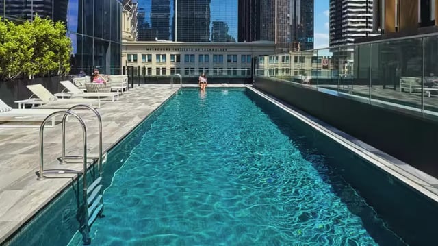 Rooftop pool with loungers and city view exterior at Scape Aurora in Melbourne Student Accommodation
