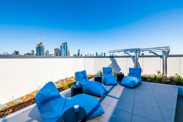 Blue lounge chairs and tables on rooftop patio at Scape Peel in Melbourne Student Accommodation
