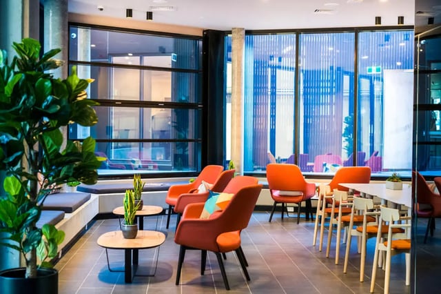 Orange chairs, tables, plants, lounge area at Scape Peel in Melbourne Student Accommodation