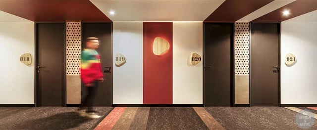 Corridor with doors numbered 818-821 and a person hallway at EPIISOD Macquarie Park in Sydney Student Accommodation