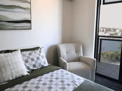 Bed armchair artwork and balcony view bedroom at Student Living - Shafston in Brisbane Student Accommodation
