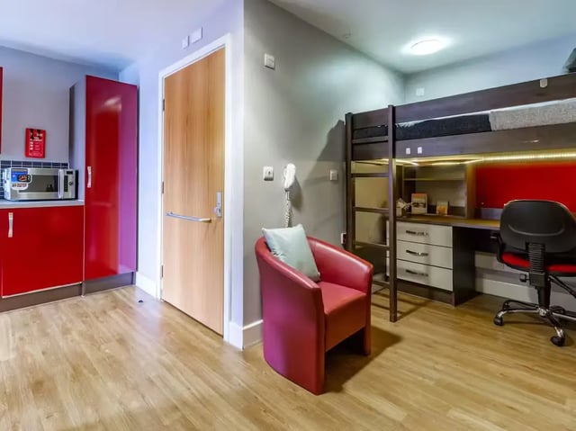 Bunk bed desk chair armchair and kitchen living room at Camden Hawley Crescent in London Student Accommodation