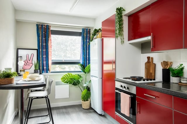 Red cabinets stove fridge with table and chairs Kitchen at Rahere Court in London Student Accommodation