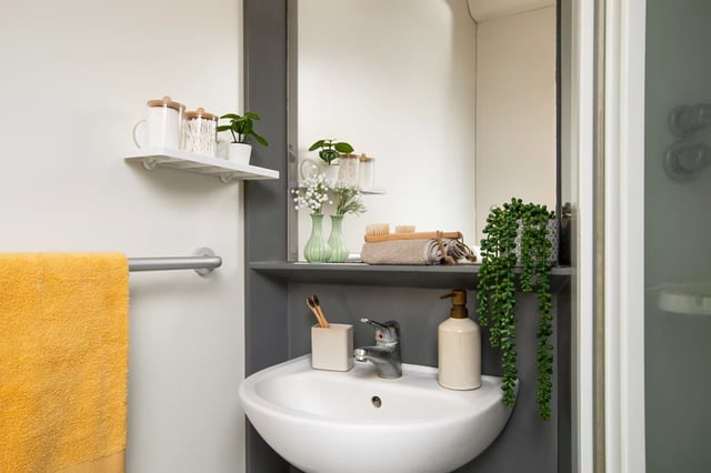 Sink with soap dispenser and yellow towel Bathroom at Wellington Lodge in London Student Accommodation
