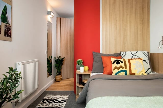 Bed with patterned pillows radiator and plants Bedroom at Wellington Lodge in London Student Accommodation
