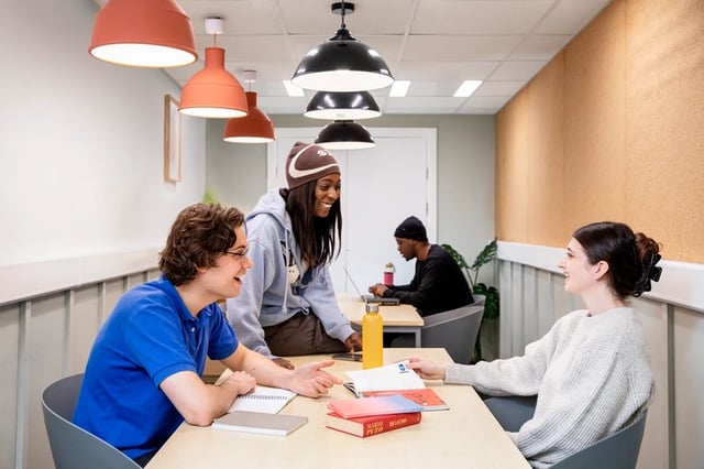 Students studying at tables with books and laptops common area at Wellington Lodge in London Student Accommodation