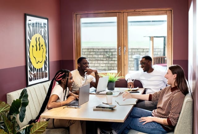 Students working on laptops at a communal table at Piccadilly Court in London Student Accommodation