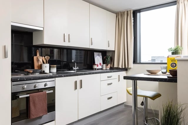 White cabinets stove sink and breakfast bar kitchen at Olympic Way in London Student Accommodation