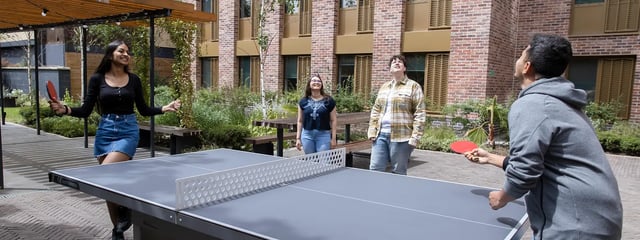 Four students playing table tennis outdoors Courtyard at The Valentine London in London Student Accommodation
