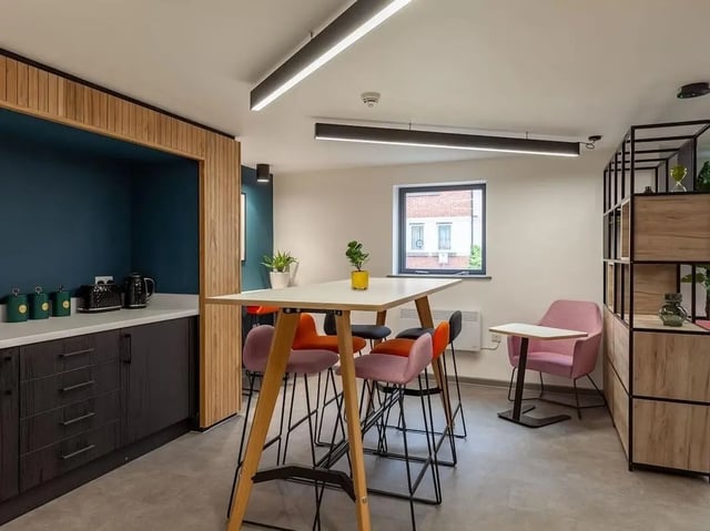 Kitchen area with high table chairs and pink armchair communal area at Devonshire Courtyard in Sheffield Student Accommodation