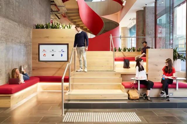 Students relaxing on red couch stairs and tables living room at Scape Swanston in Melbourne Student Accommodation