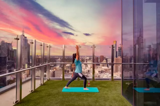 Yoga on rooftop with city view exterior at Scape Swanston in Melbourne Student Accommodation