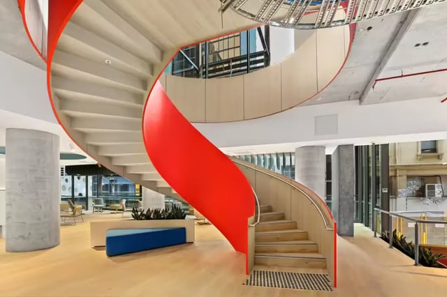Red spiral staircase with seating area common area at Scape Swanston in Melbourne Student Accommodation