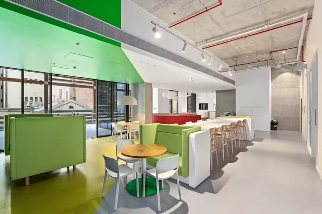 Green booths white chairs tables communal area living room at Scape Swanston in Melbourne Student Accommodation
