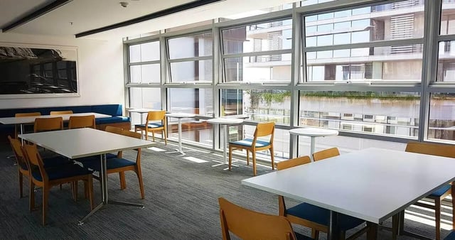White tables blue chairs large window communal area at Iglu Central Park in Sydney Student Accommodation
