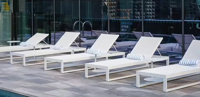 White lounge chairs with rolled towels pool area exterior at Scape Aurora in Melbourne Student Accommodation